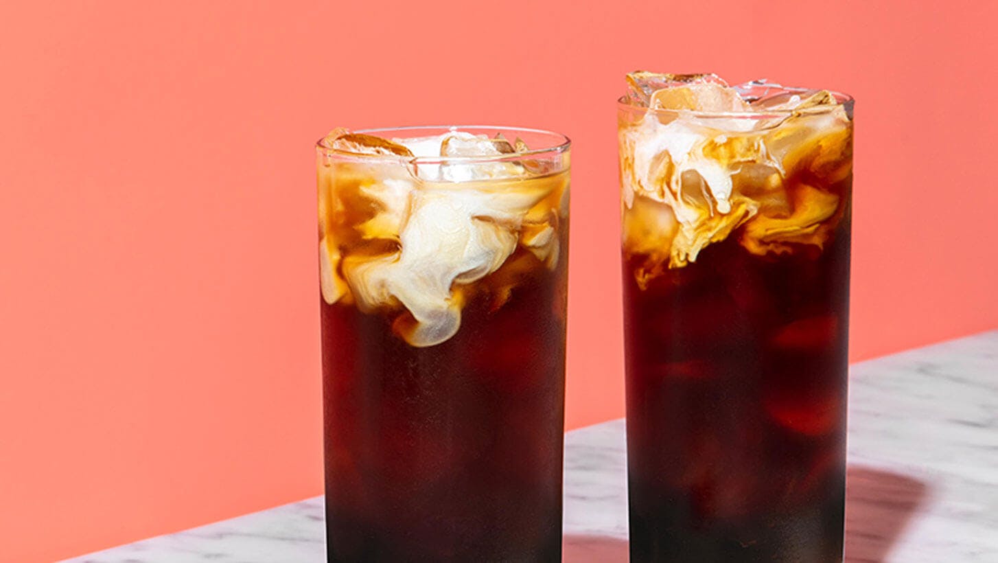 Cup of cold brew coffee over ice with a splash of creamer